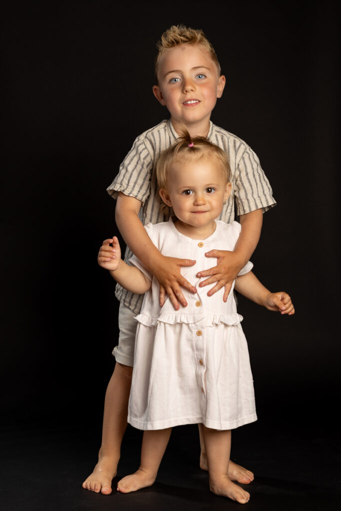 skolefotografering i studiet hos Winther sol foto, på sort baggrund. Søskende fotografering