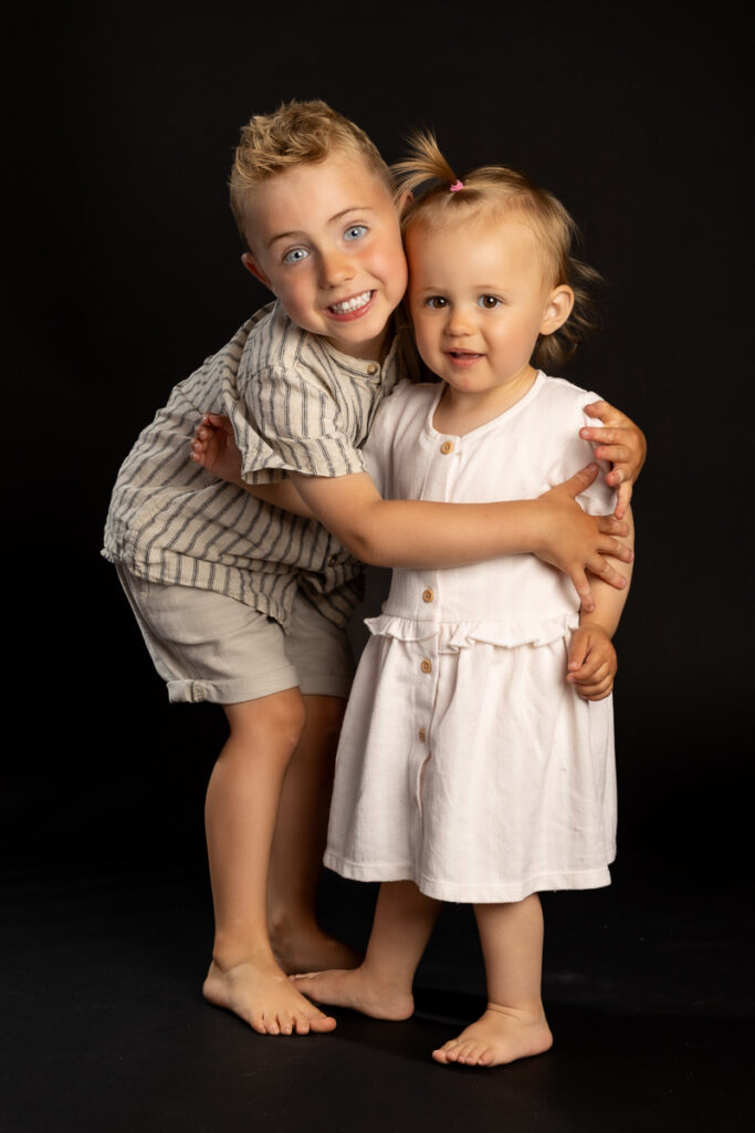 skolefotografering i studiet hos Winther sol foto, på sort baggrund. søskendefotografering